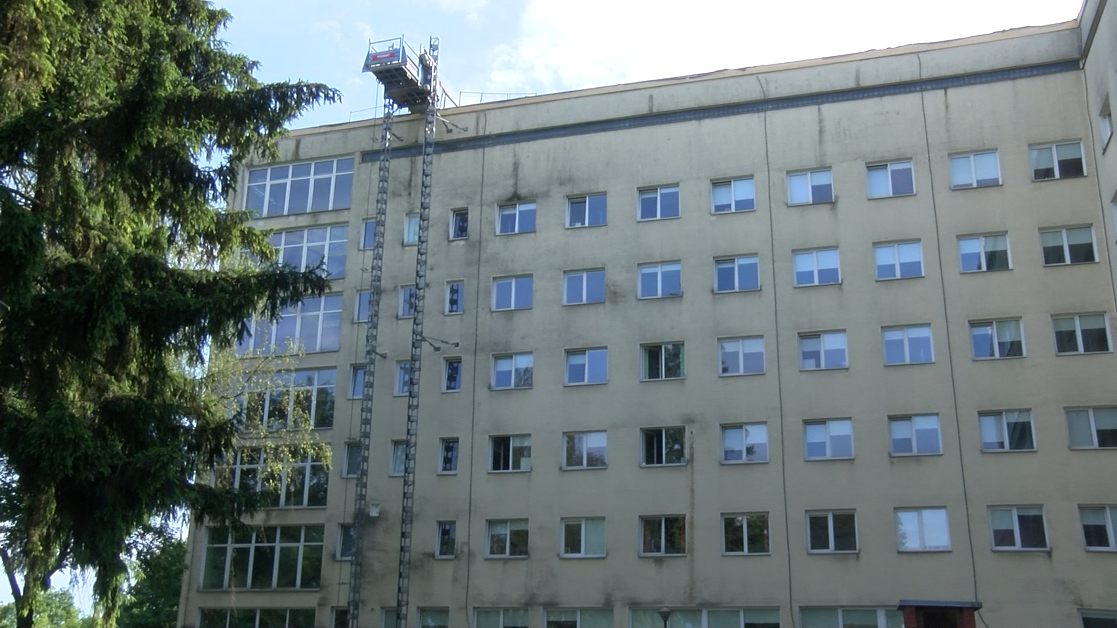 Ēkas fasādes remontdarbi ar pacēlāju pie daudzstāvu ēkas