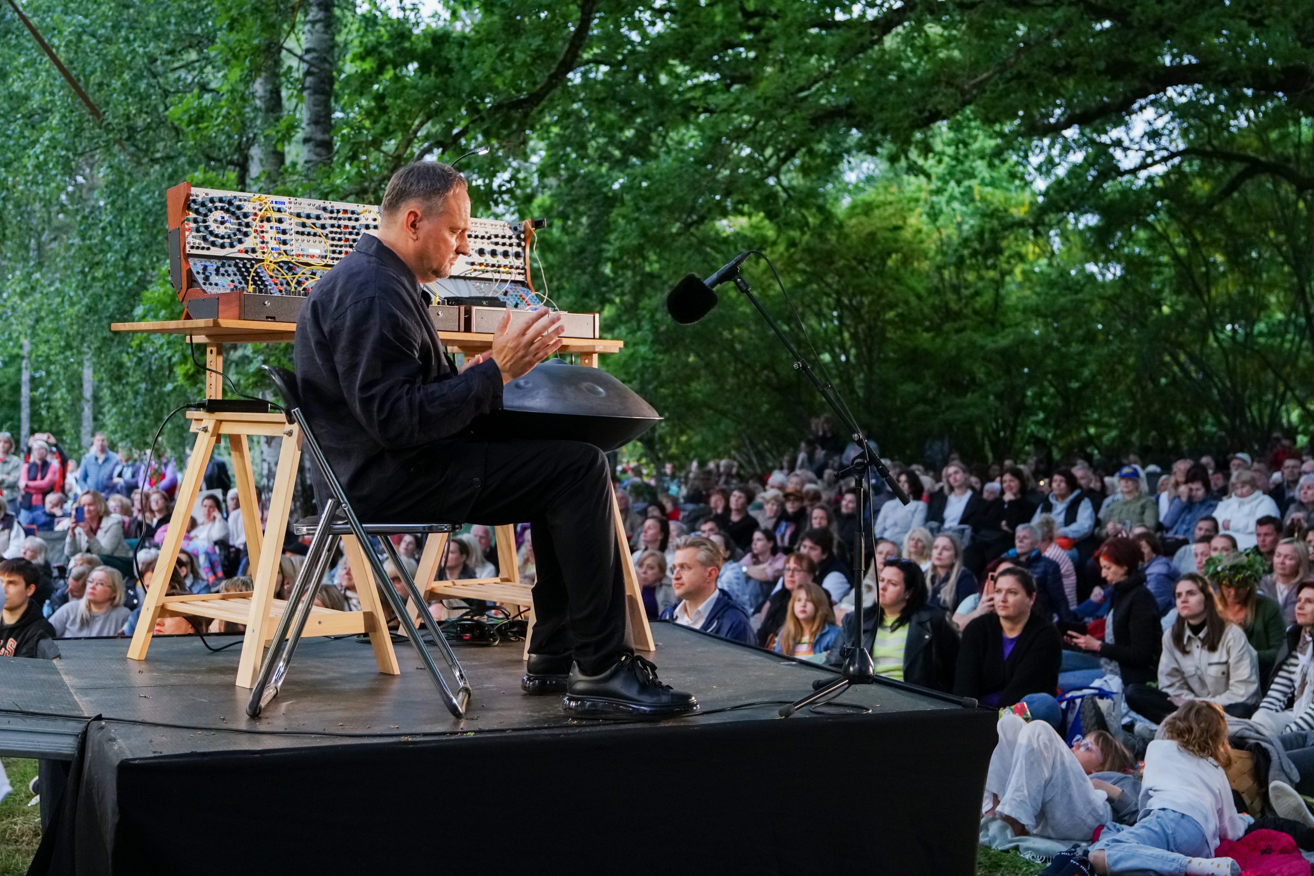 Komponists Raimonds Tiguls uzstājas ar handpan instrumentu brīvdabas koncertā Tigulkalnā, skatītāji klausās dabas ieskautā vidē