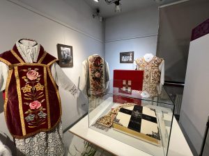 Izstādes ekspozīcija ar izšūtiem garīdznieku tērpiem un grāmatu