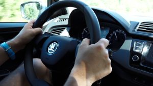 Autovadītājs pie Škoda stūres, spidometrs rāda 90 km/h