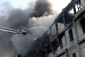 Ugunsdzēsēji dzēš ugunsgrēku daļēji sabrukušā ēkā ar pacēlāju