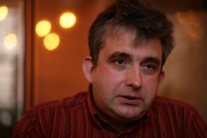 Aktieris Gundars Āboliņš sēž un skatās ar nopietnu sejas izteiksmi