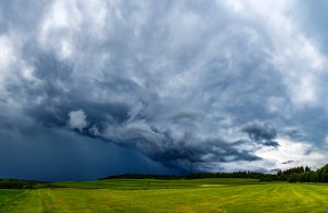 Vētras mākoņi virs zaļiem laukiem vasaras ainavā