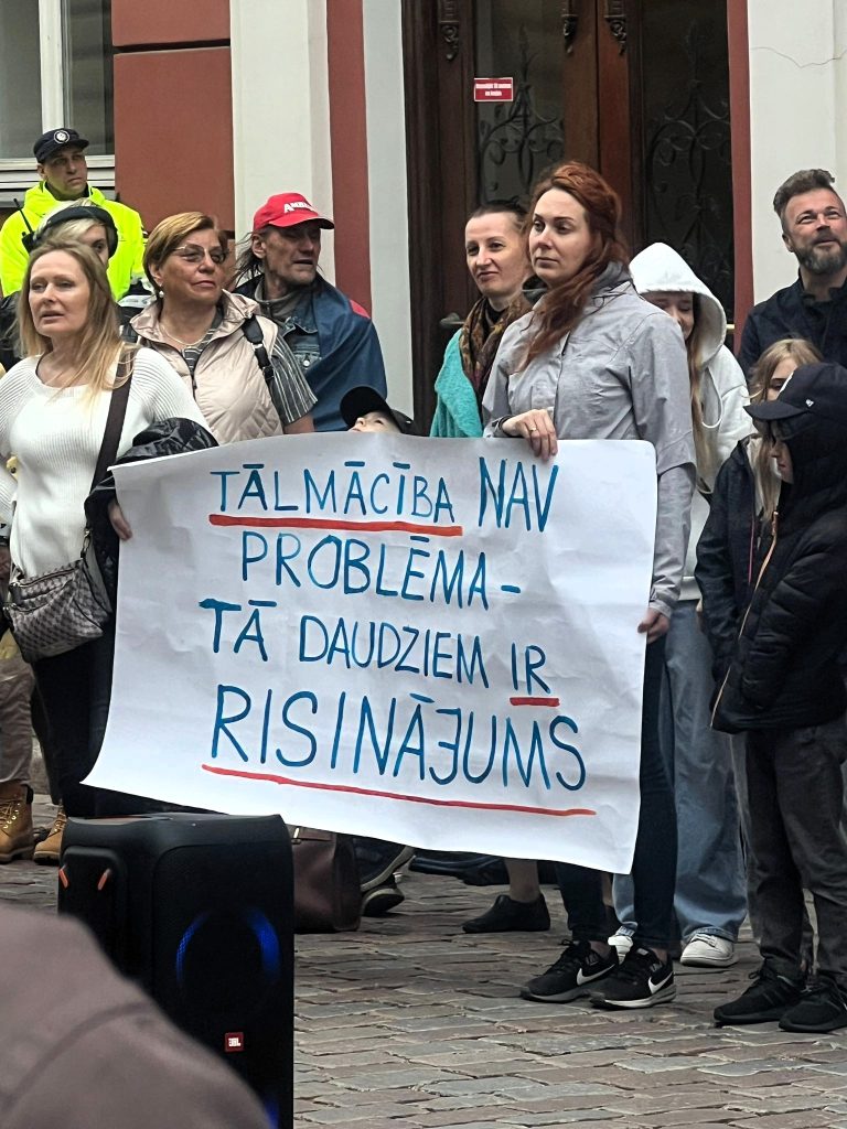 Sieviete piketā tur lielu plakātu ar uzrakstu "Tālmācība nav problēma - tā daudziem ir risinājums".