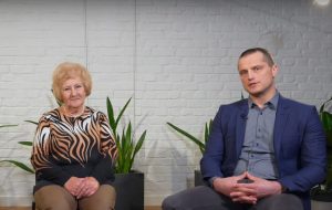 Juris Vanags un Aija Barča piedalās sarunā par redzes veselības pieejamību Latvijā, sēžot studijas interjerā ar augu fonu.