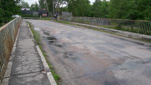 Nolietots tilts ar bedrainu asfaltu un sarūsējušām margām