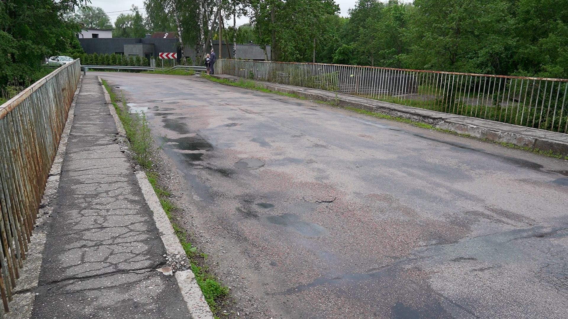 Nolietots tilts ar bedrainu asfaltu un sarūsējušām margām