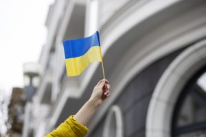 Roka tur nelielu Ukrainas karogu pret ēkas fonu