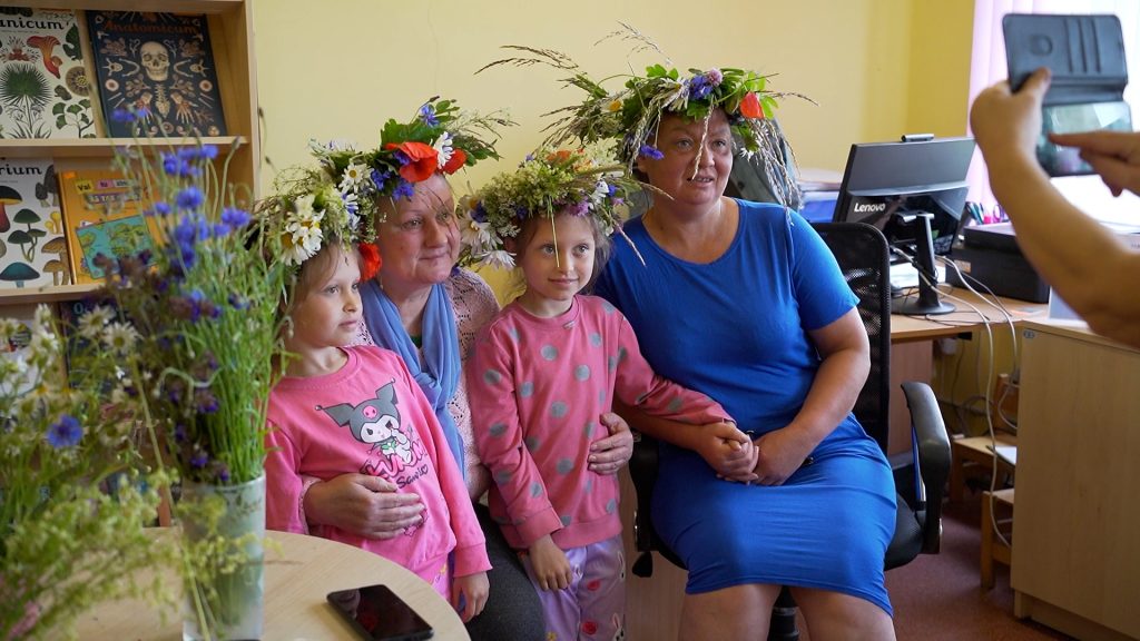Divas sievietes un divas meitenes, rotātas ar Līgo vainagiem, pozē fotogrāfijai