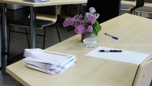 Vēlēšanu iecirknis ar dokumentiem un ceriņu vāzi uz galda