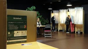 Vēlēšanu kabīnes ar balsotājiem un informāciju par balsošanas kārtību