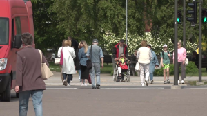 Cilvēki šķērso ielu pie gājēju pārejas ar zaļo luksofora signālu