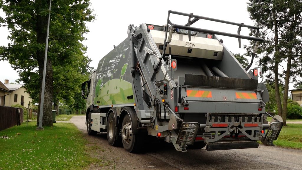 ZAAO elektriskais atkritumu vedējs no aizmugures leņķa, kas stāv uz ceļa