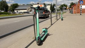 Zaļš elektroskrejritenis novietots uz ietves pie ielas Valmierā.