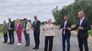 Amatpersonas svinīgi pārgriež lentu, atklājot atjaunoto ceļa posmu Bauskas novadā