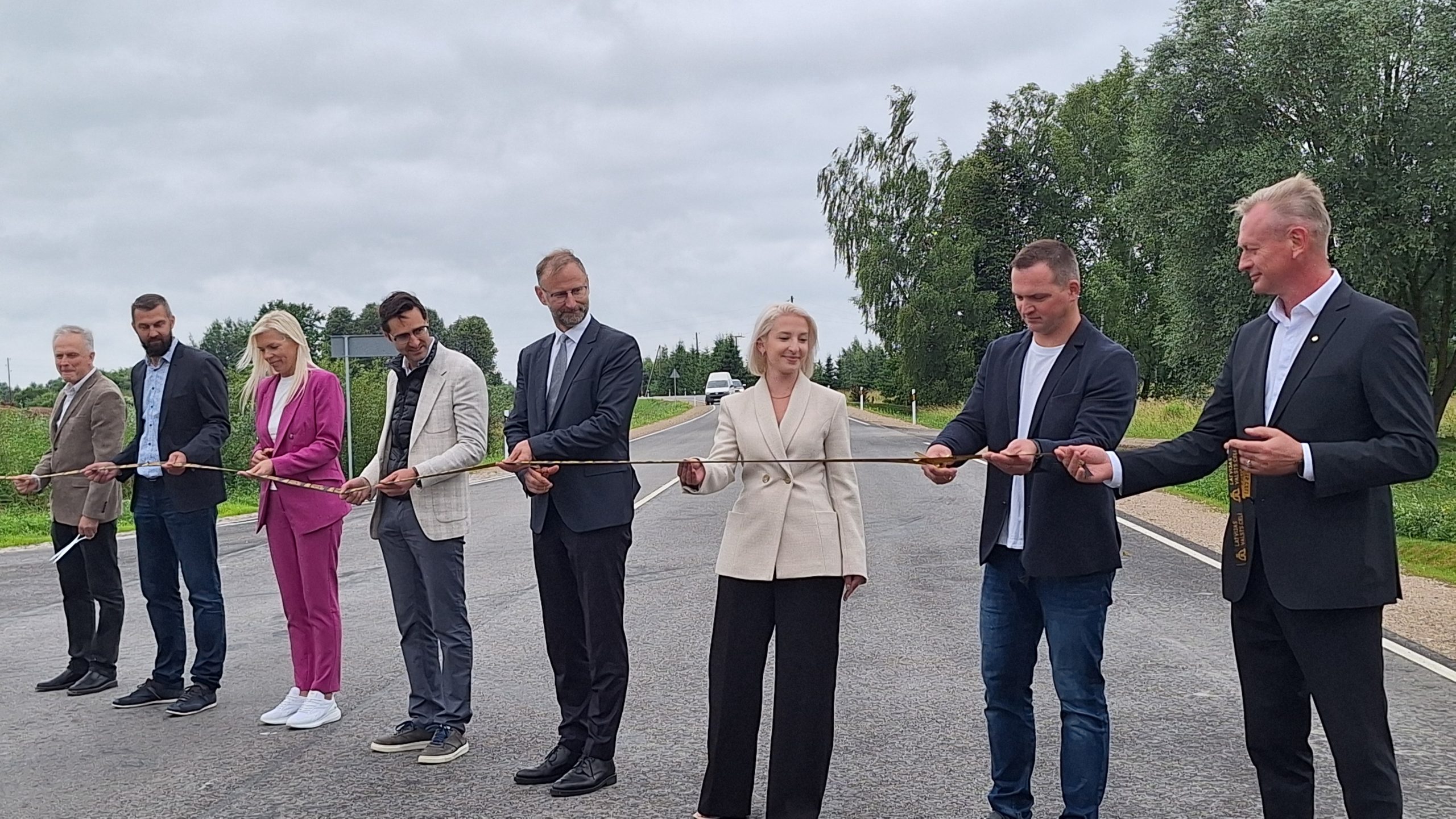 Amatpersonas svinīgi pārgriež lentu, atklājot atjaunoto ceļa posmu Bauskas novadā