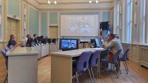 Deputāti sēdes laikā Dobeles novada domes zālē pie datoriem un ekrāniem.
