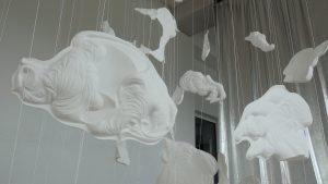 Tuvplāna skats uz baltiem peldošiem porcelāna objektiem laikmetīgās mākslas instalācijā