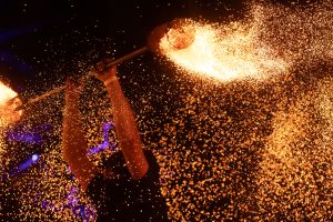 Uguns šovs Valmiermuižas etnomūzikas festivālā 2025. gadā tumsā ar dzirkstelēm un liesmu efektu