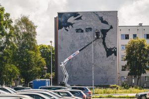 Franču ielu mākslinieks Aéro strādā pie liela sienas gleznojuma "Sirmgalvis un jūra" uz ēkas sienas Liepājā, izmantojot pacēlāju