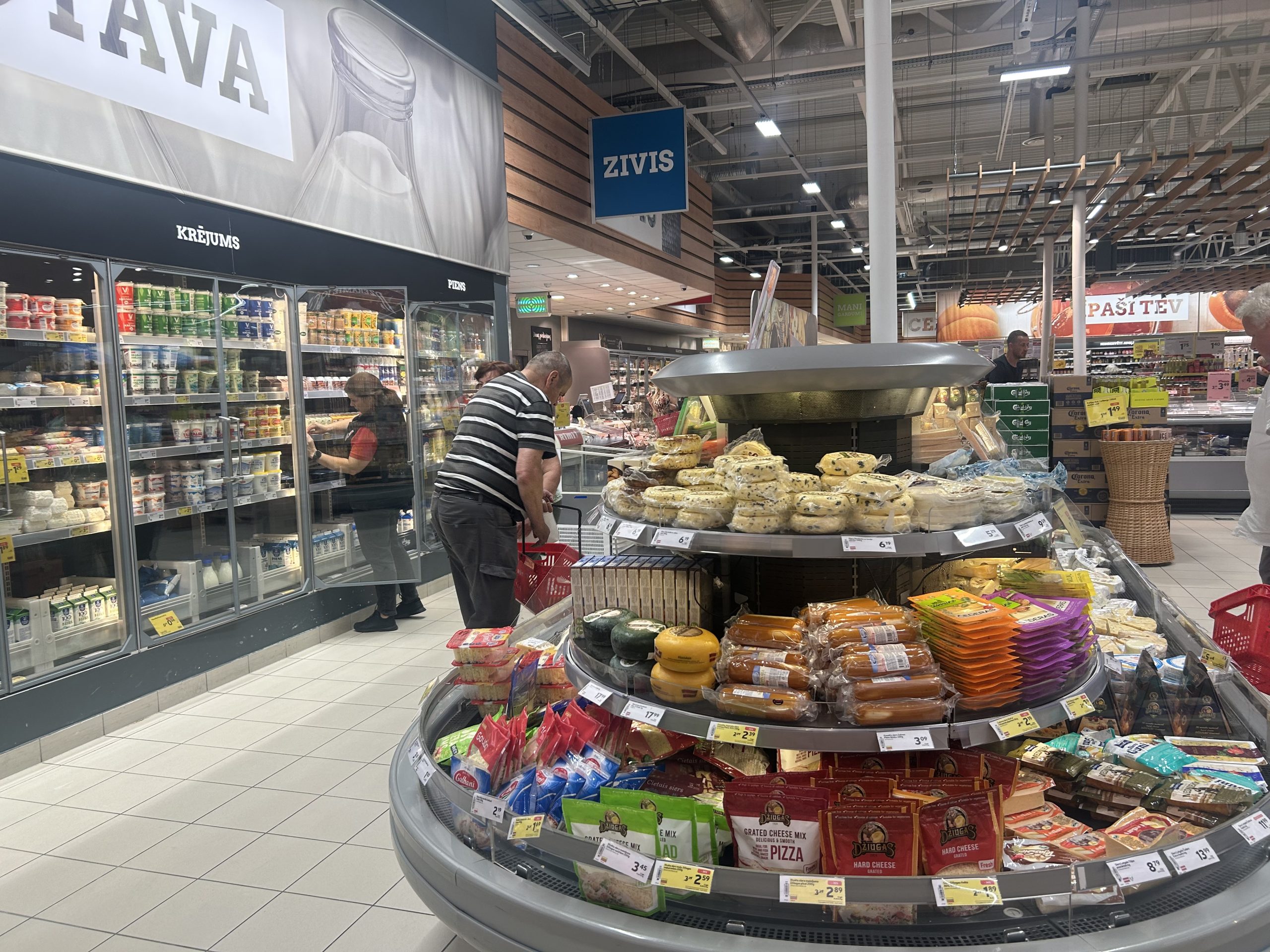 Pircēji aplūko pārtikas preces veikala piena un sieru nodaļā.
