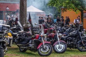 Motociklistu salidojums meža ielokā ar nometnes teltīm un spēkratiem