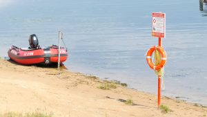 Glābšanas riņķis un laiva pie ūdens krasta smilšainā pludmalē