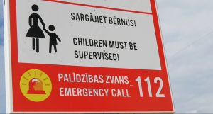 Brīdinājuma zīme ar uzrakstu “Sargājiet bērnus!” un ārkārtas tālruni 112