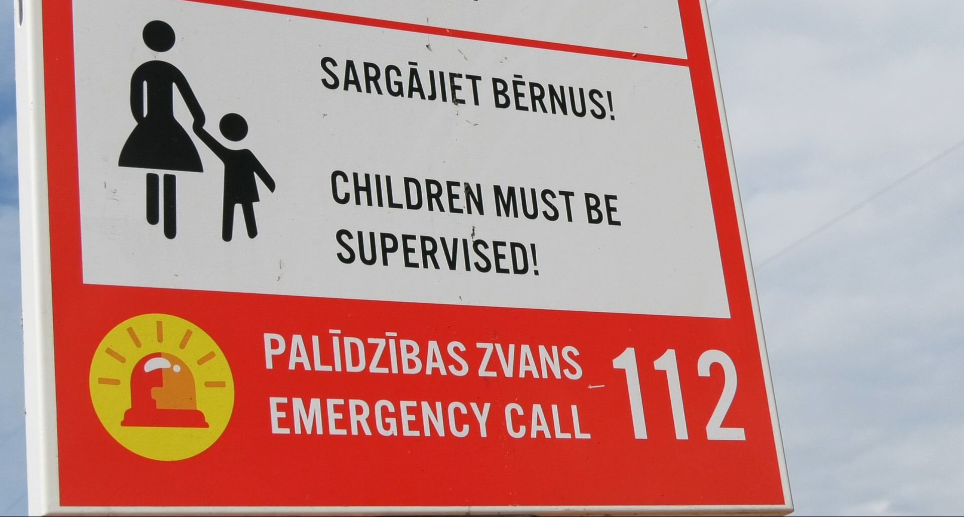 Brīdinājuma zīme ar uzrakstu “Sargājiet bērnus!” un ārkārtas tālruni 112