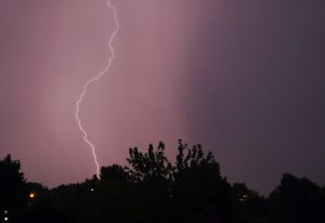 Zibens spēriena brīdis negaisa laikā virs koku silueta Latgalē.