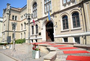 Latvijas Universitātes galvenā ēka ar sarkanajiem paklājiem pie ieejas.