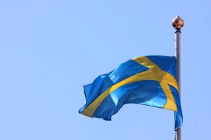 Zviedrijas karogs plīvo debesu fonā.