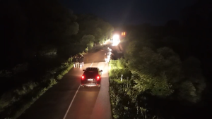 Naktī applūdis ceļš ar automašīnām un cilvēkiem, kas vēro notiekošo