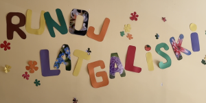 Uz sienas pielikts uzraksts "RUNOJ LATGALISKI" no krāsainiem burtiem