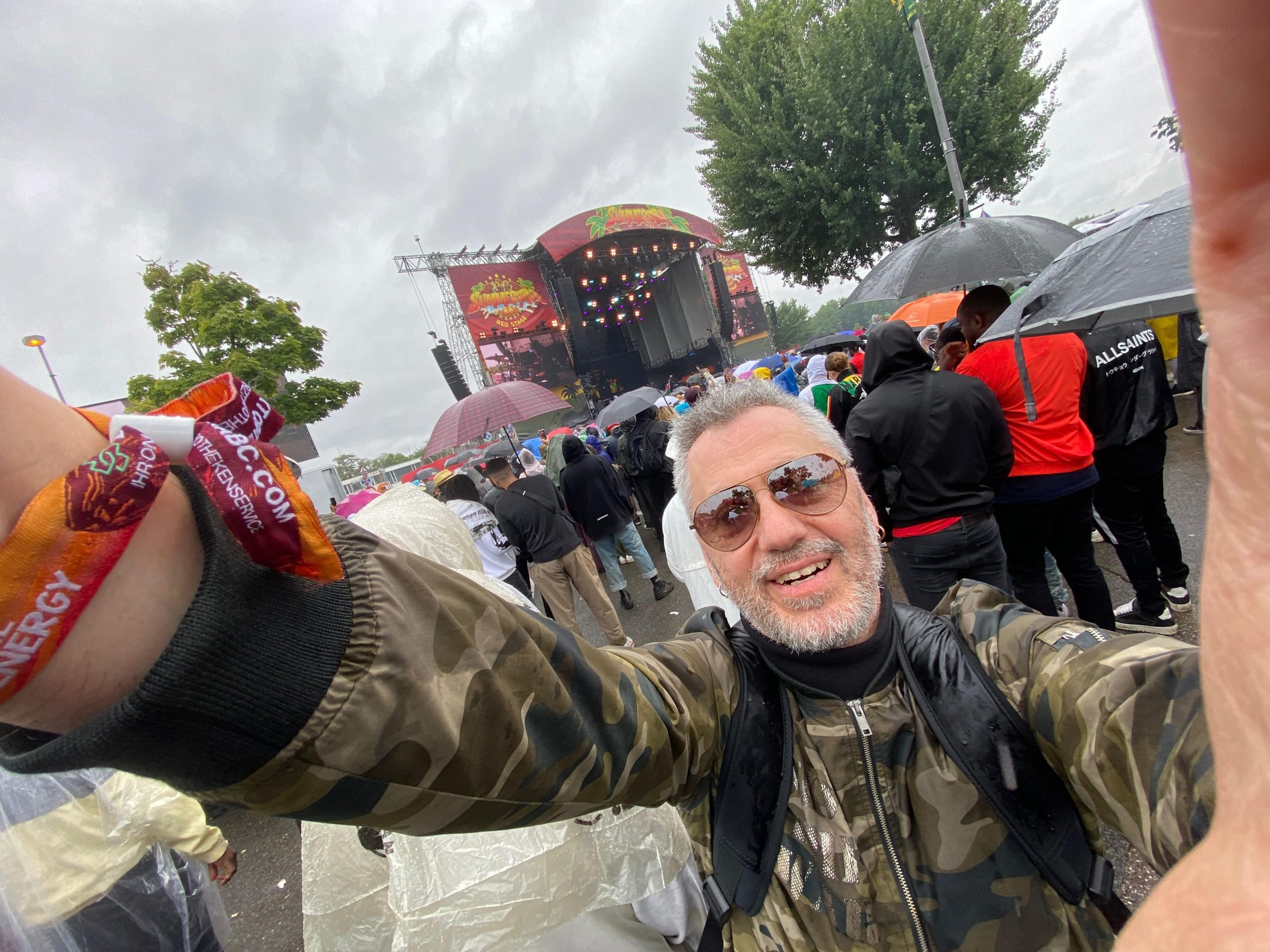 Horens Stalbe smaidot fotografē selfiju pie Summerjam festivāla skatuves lietainā laikā