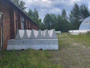 Betona barjeras pie ķieģeļu noliktavas ēkas