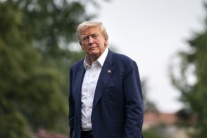 ASV prezidents Donalds Tramps uzvalkā stāv ārā, fonā koki