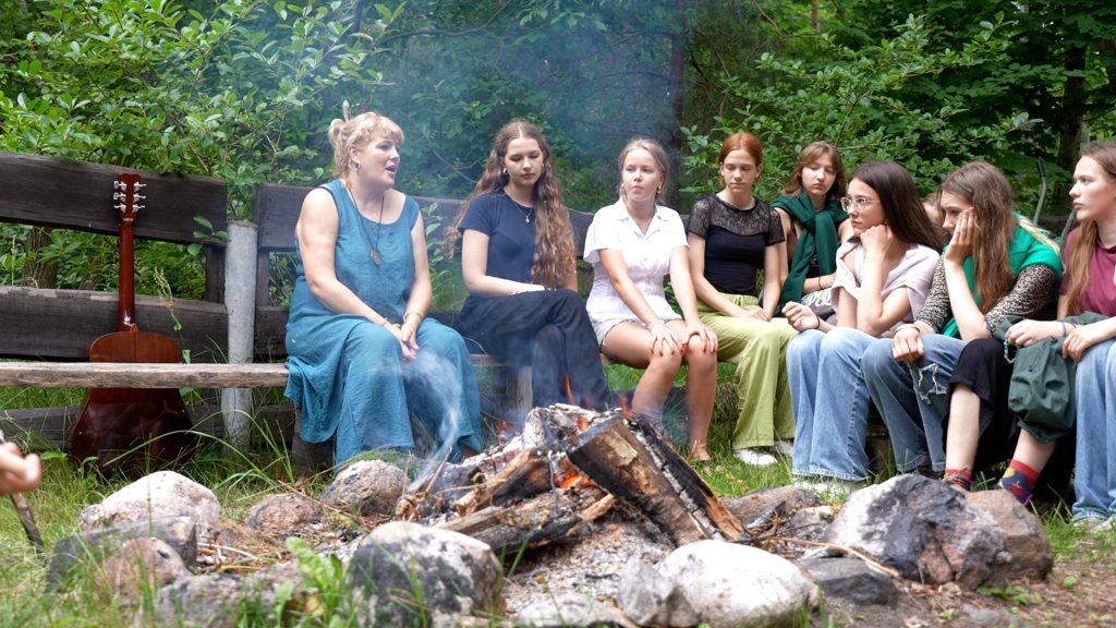 Lībiešu vasaras skolas "Mierlinkizt" dalībnieki sēž ap ugunskuru un dzied