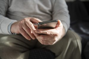 Vecāka gadagājuma cilvēks lieto viedtālruni