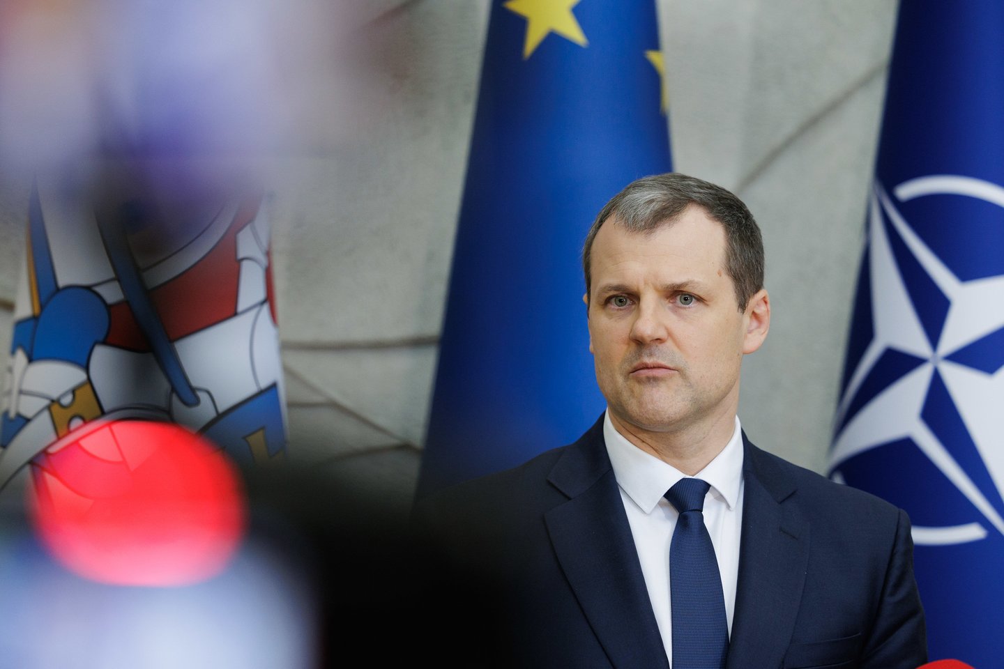Lietuvas premjerministrs preses konferencē pie ES un NATO karogiem.