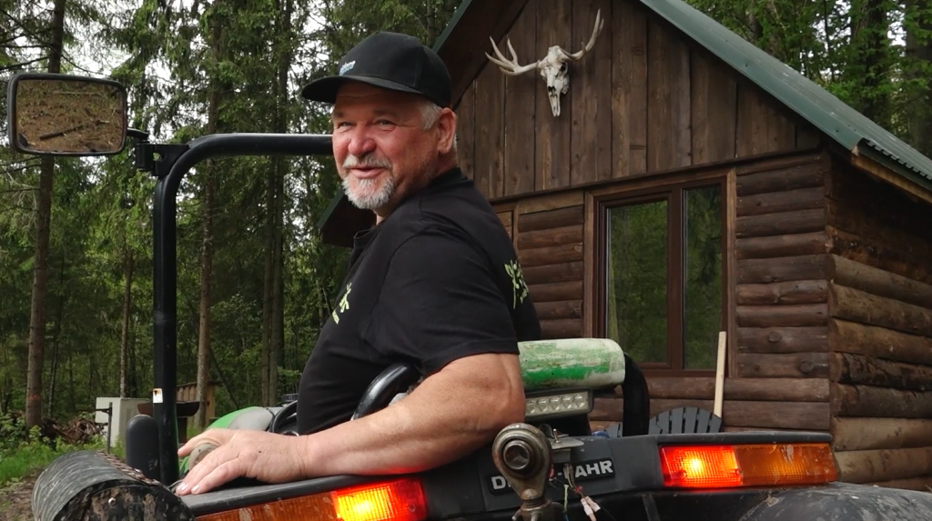 Jānis Vīksne sēž uz Pupsikbāņa traktora, smaidošs
