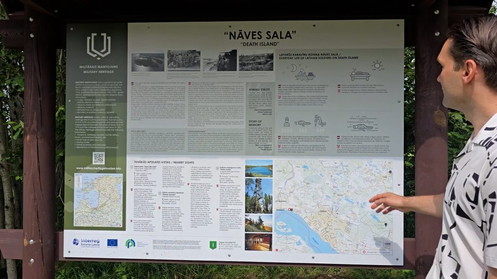 Vīrietis aplūko informatīvu stendu par Nāves salu Ikšķilē.