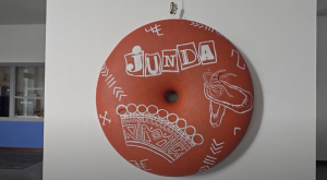 Mākslas objekts ar uzrakstu "Junda" un tautas motīviem uz sienas
