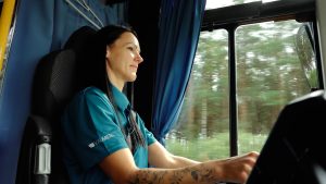 Autobusa vadītāja pie stūres, braucot pa meža ceļu