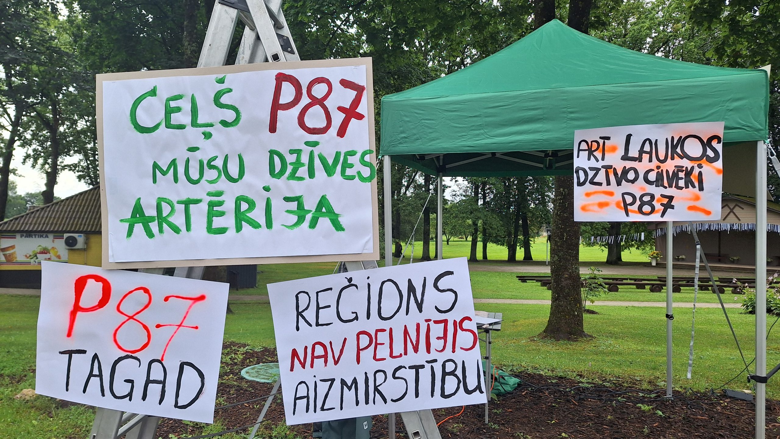 Piketā izkārtoti plakāti ar saukļiem par P87 ceļa stāvokli Bārbeles pagastā.