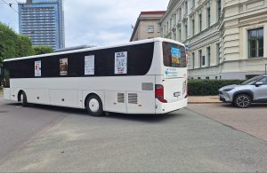 Balts autobuss ar protesta plakātiem par pasažieru pārvadājumu reisu slēgšanas nepieļaušanu.