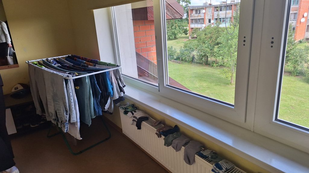 Veļas žāvēšanas statīvs istabā pie loga bērnu atbalsta centrā.