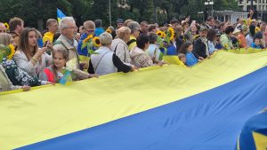 Cilvēki ar saulespuķēm un Ukrainas karogu lielā gājienā Rīgā