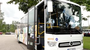 Baltas krāsas sabiedriskais autobuss ar atvērtām durvīm un velo simboliku