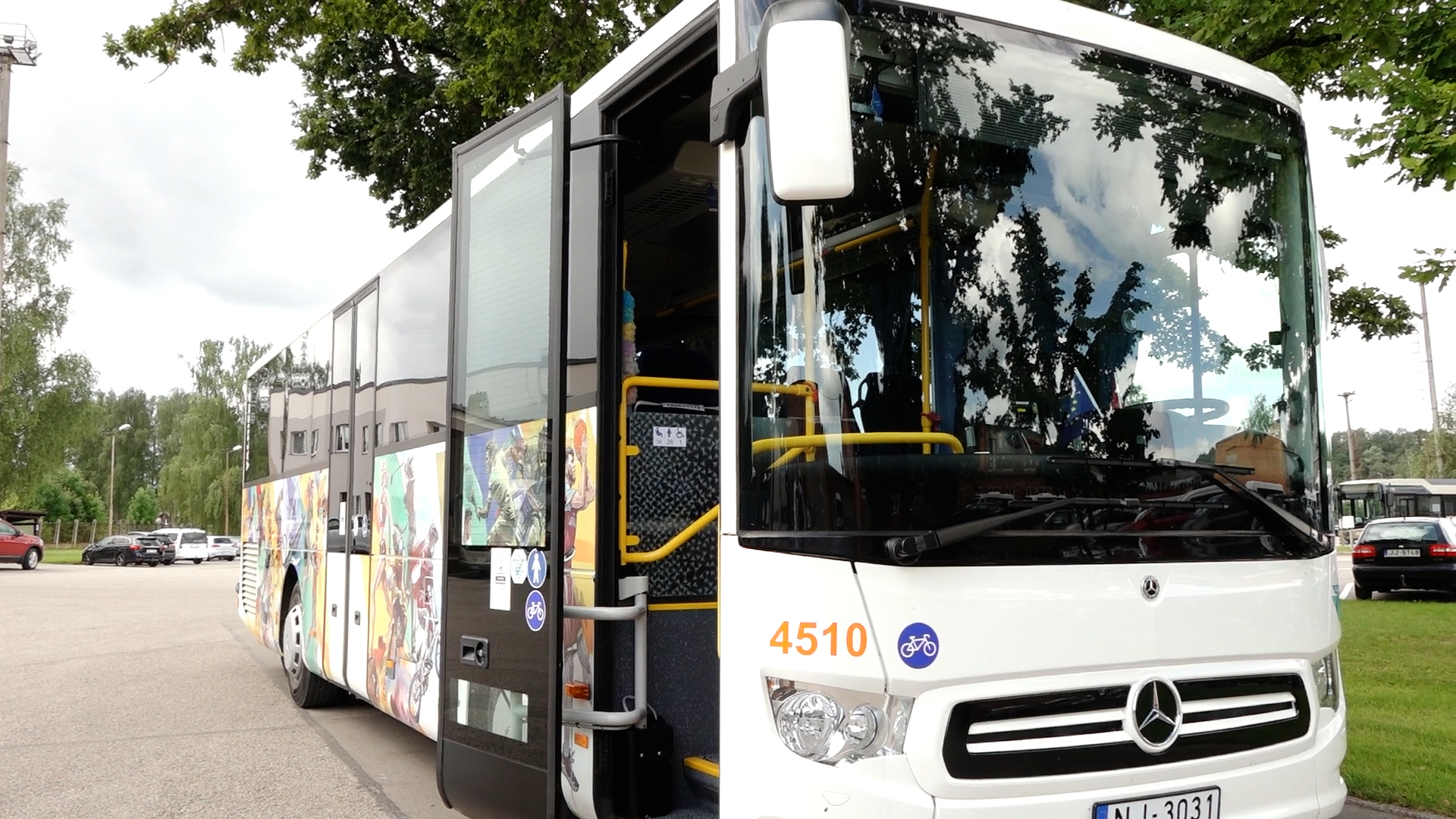 Baltas krāsas sabiedriskais autobuss ar atvērtām durvīm un velo simboliku